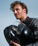 A man holding a motorcycle helmet wearing Alpine MotoSafe earplugs.