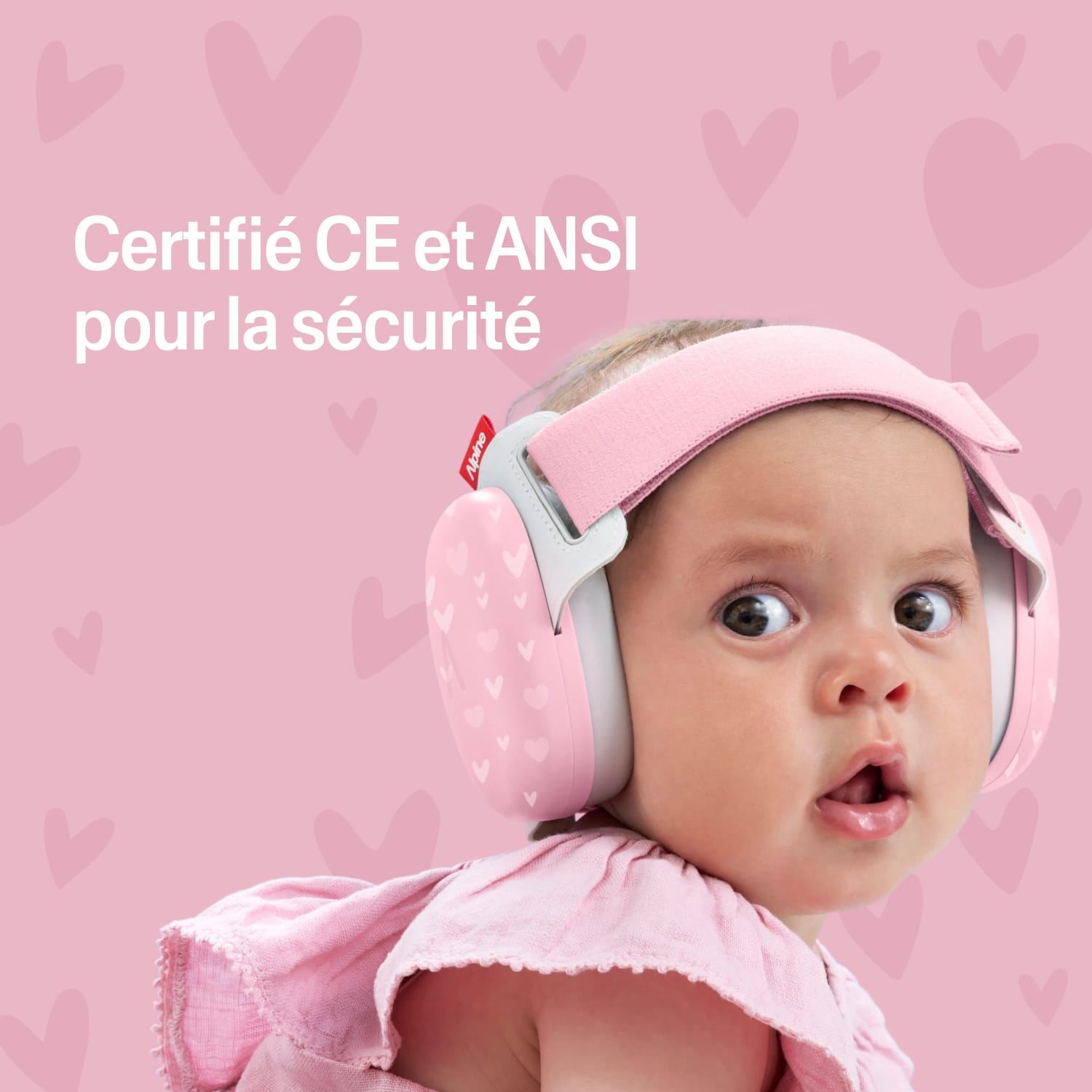 Baby wearing a pink muffy baby with certification text on a pink heart-patterned background