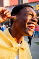 Person with a yellow jacket laughing outdoors with a blurred background