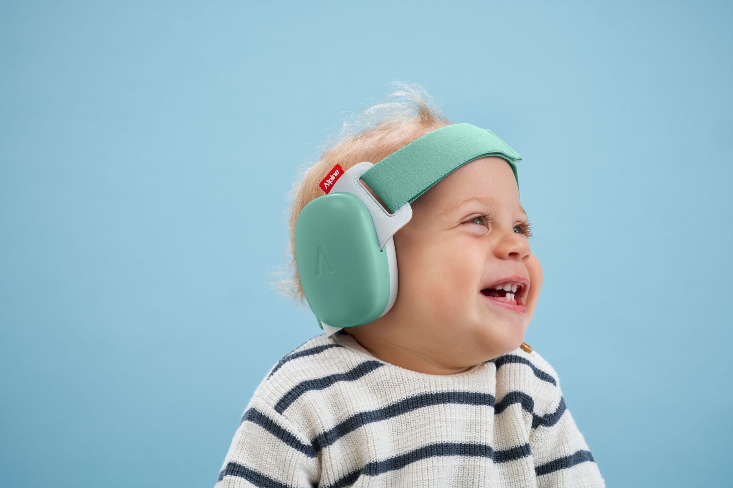 Baby with blonde hair, with Muffy Baby on its head, smiling