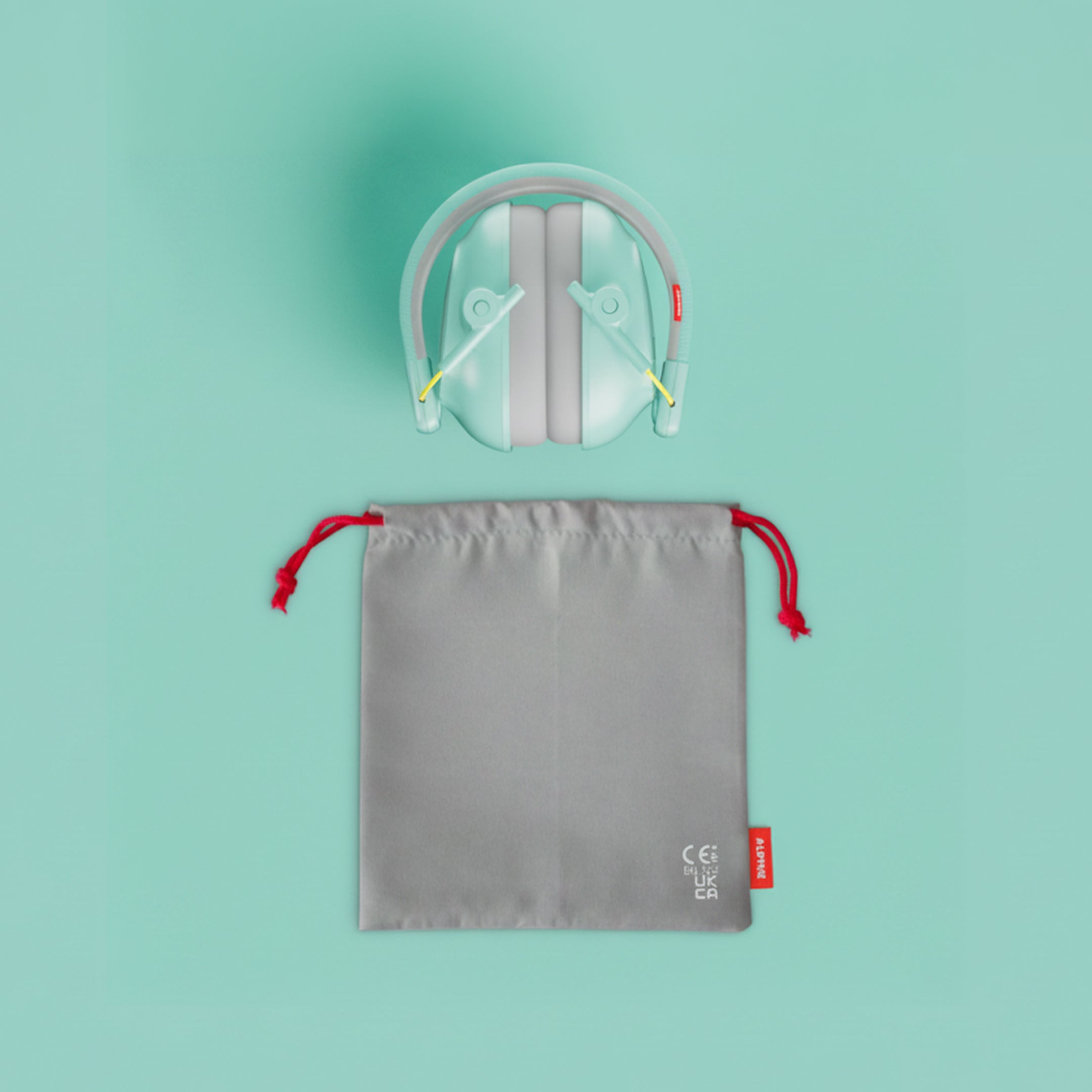 Alpine Muffy Baby ear defenders in mint, folded, with grey carrying pouch 